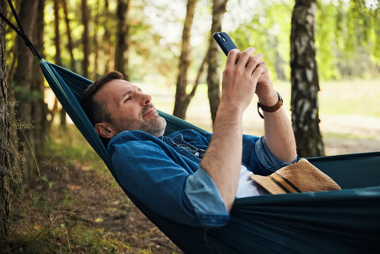 Man laying on a hammock looking at phone