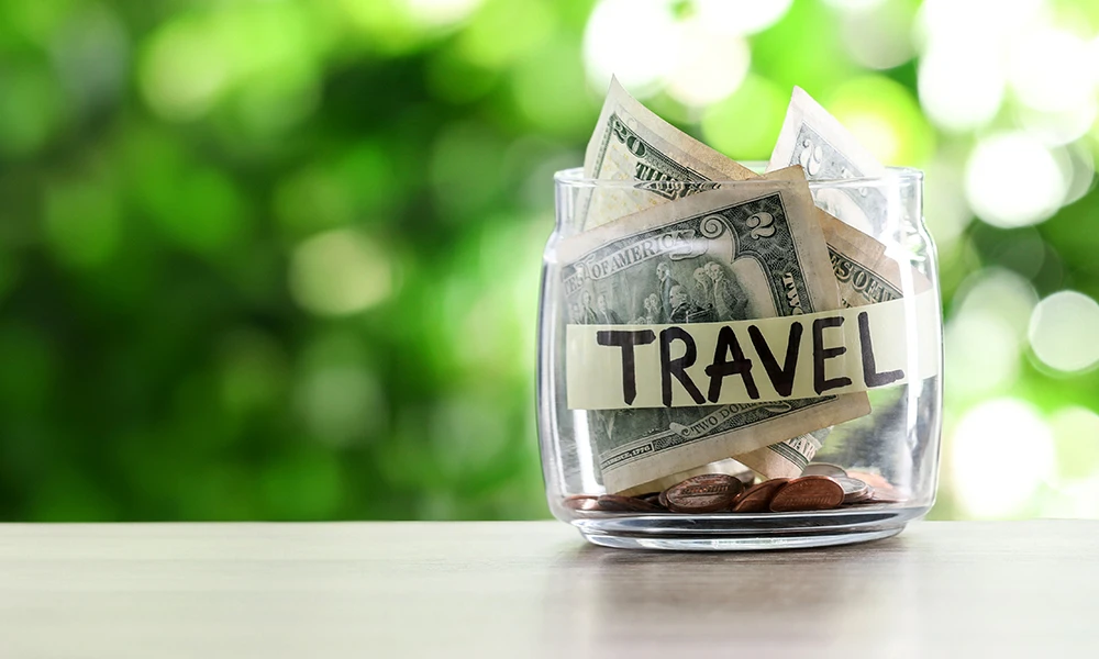 clear glass jar stuffed full money with the word Travel written on it