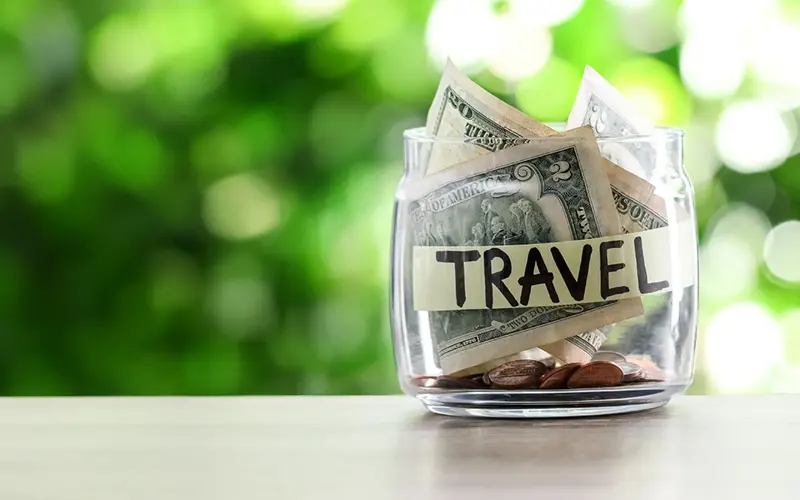clear glass jar stuffed full money with the word Travel written on it