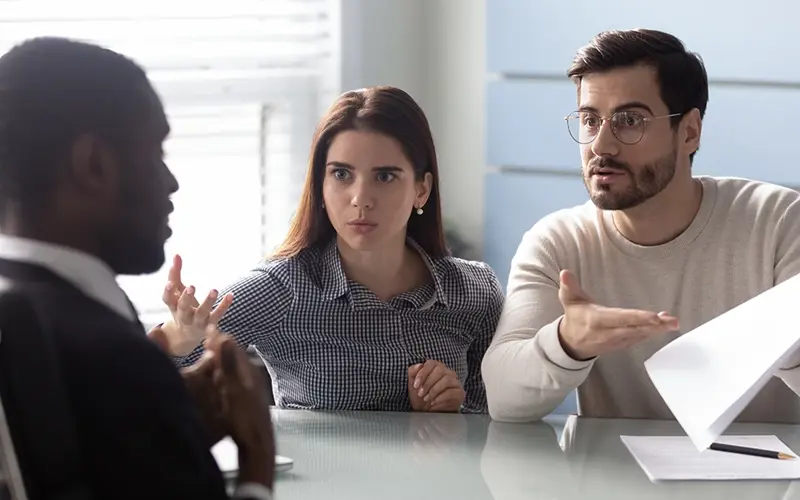 couple talking to advisor looking surprised 