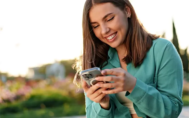 Young woman using phone and smiling