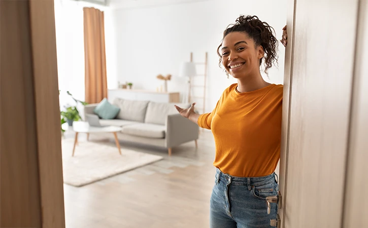 young woman welcoming a guest at her front door 
