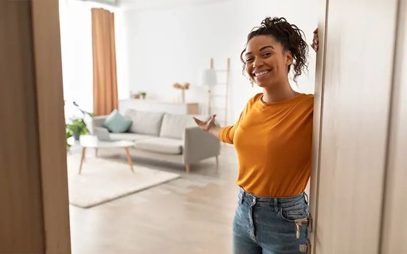 young woman welcoming a guest at her front door 