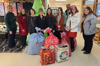 F&M Trust employees posing in the school with a few festive bags of donated items.