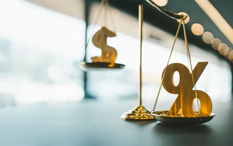 the scales of justice balancing a money sign and a percentage sign
