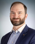 Image of Dave Long wearing a light blue and white striped shirt with a navy blazer.