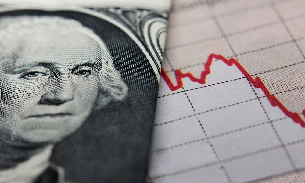 Washington's face on a dollar bill next to a paper showing a rate that is dropping