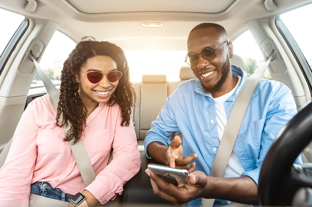 Man and woman in car looking at cell phone