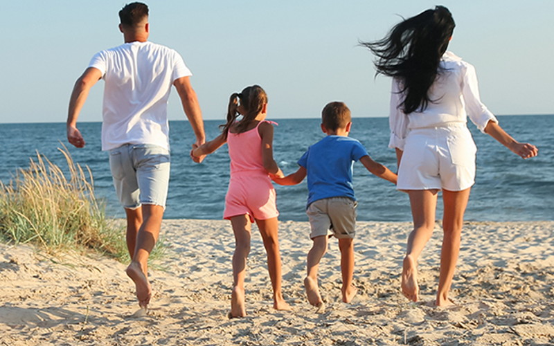 Family running on a beach holding hands