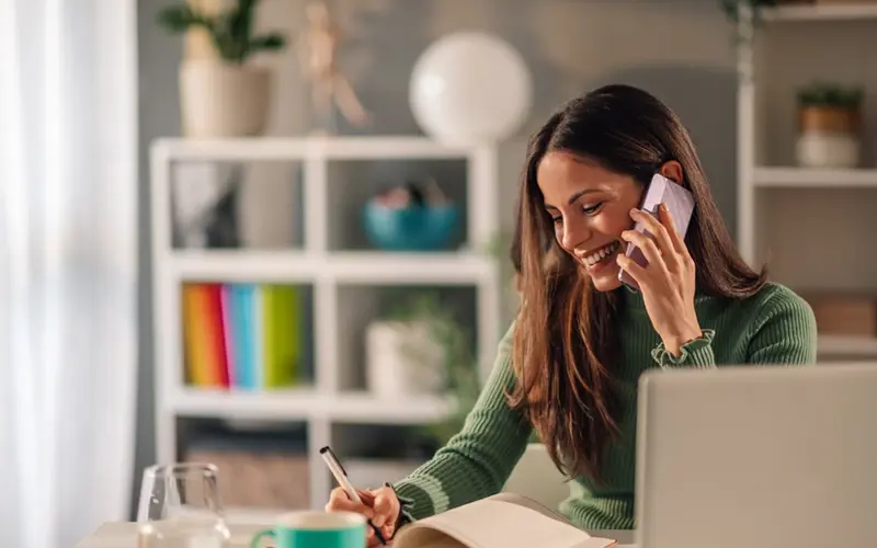 Woman on phone writing in a book