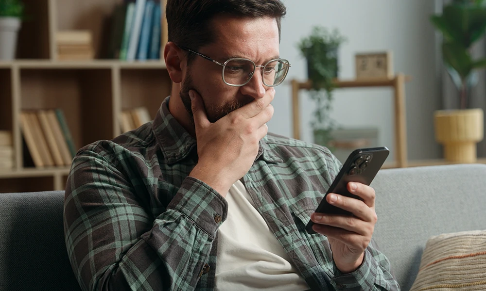 concerned man stares at mobile phone