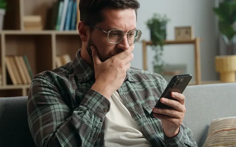 concerned man stares at mobile phone
