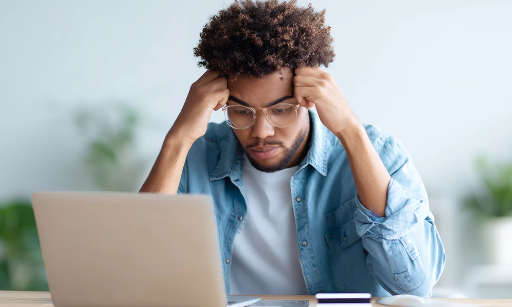 worried looking man staring at laptop screen
