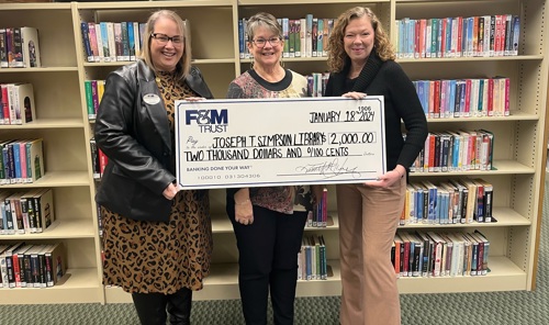Two F&M Trust employees presenting a large check to a Joseph T. Simpson Library employee.
