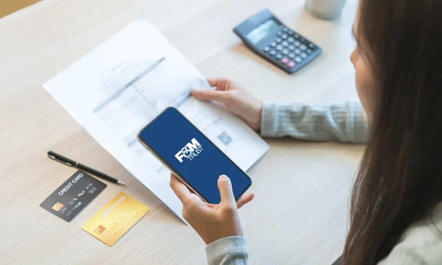 person using F&M Trust app while reviewing bills 