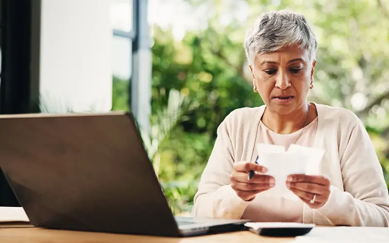 older woman reviewing receipts next to a calculator