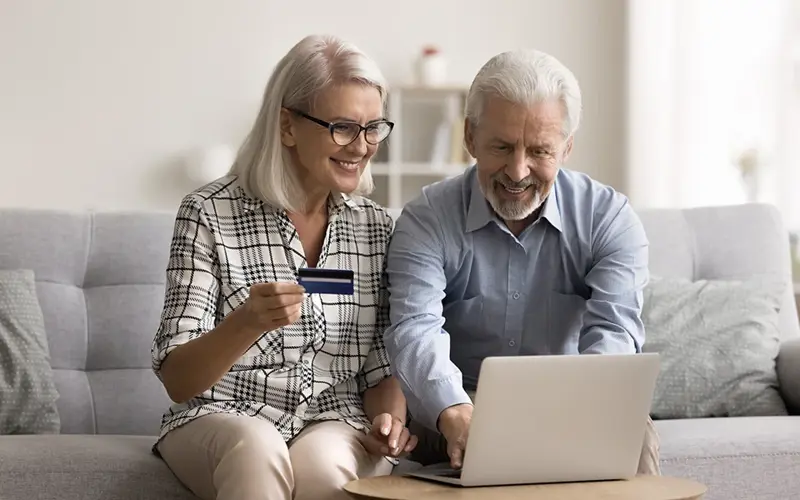 happy older couple buying something online with a credit card