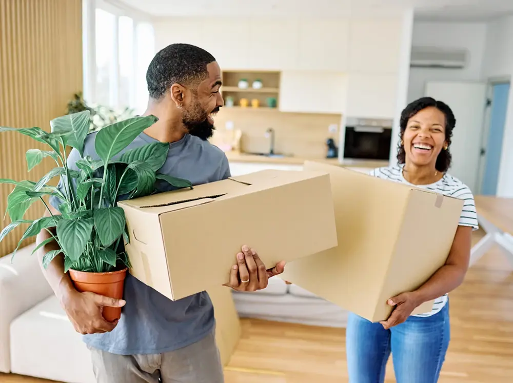 Man and woman moving boxes and a plant