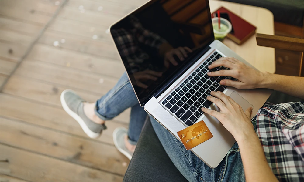 person using credit card to shop on laptop