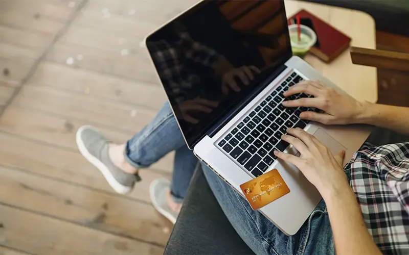 person using credit card to shop on laptop