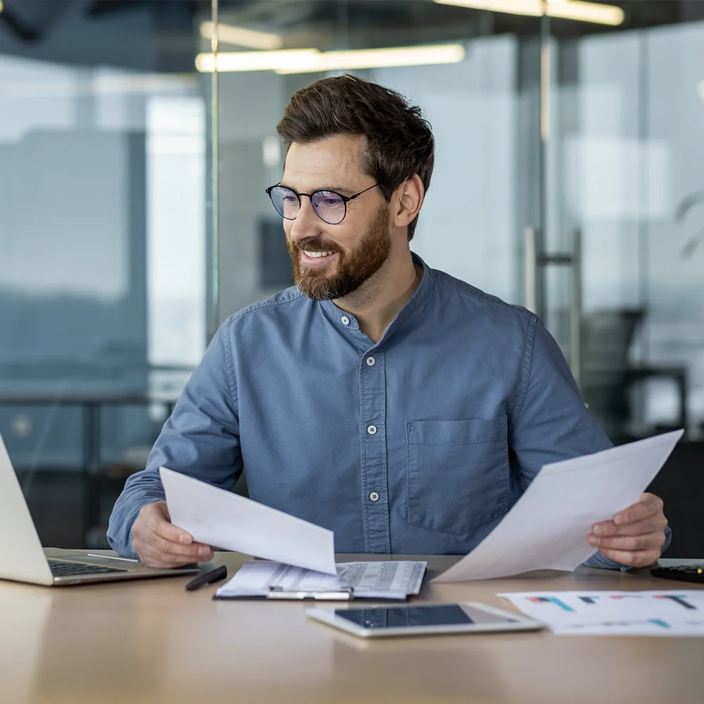 Smiling businessman working with documents and laptop