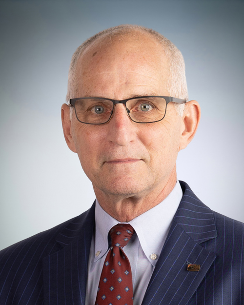 Headshot of Mark Hollar wearing glasses, a navy suit and maroon tie.