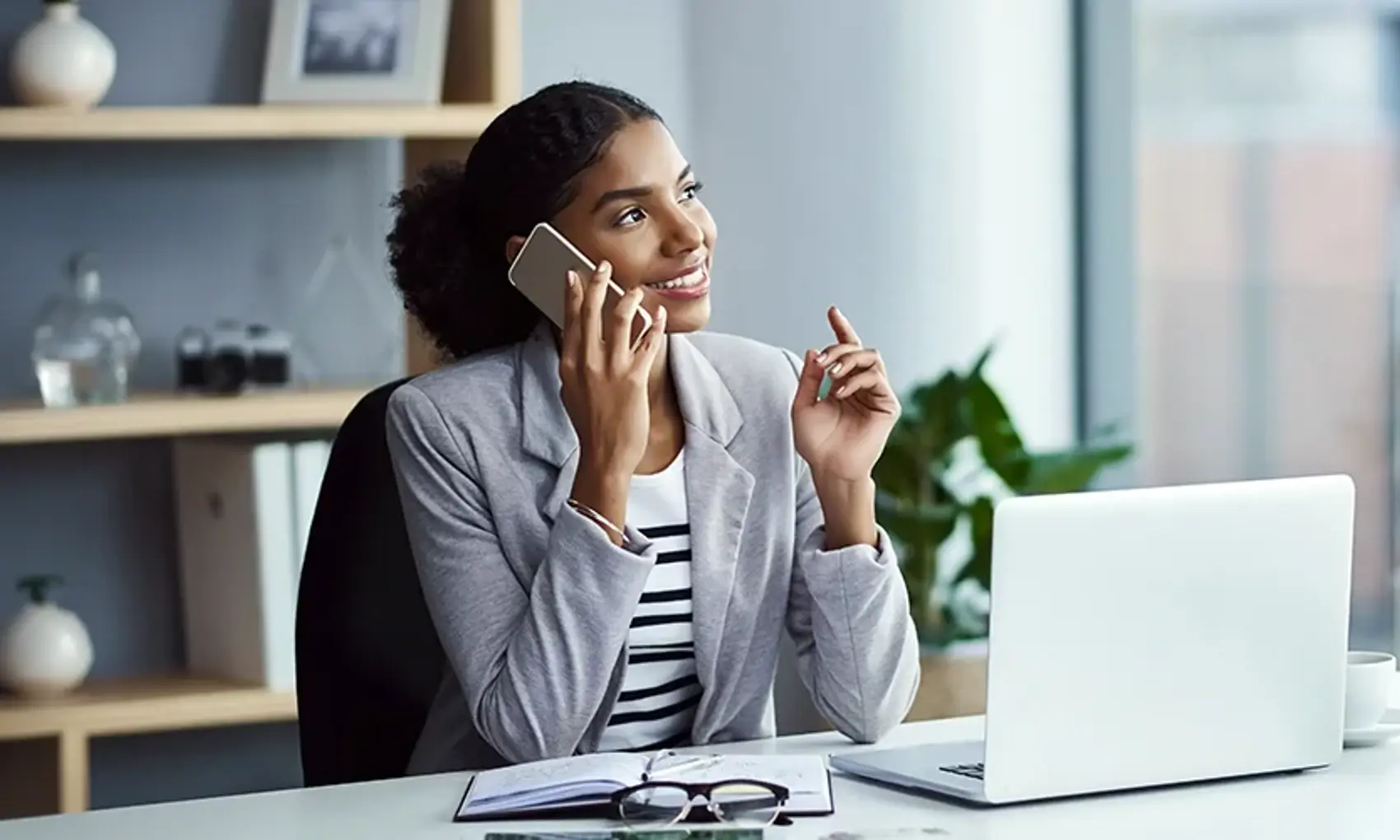 Shot of a young businesswoman using a mobile phone at her desk in a modern office