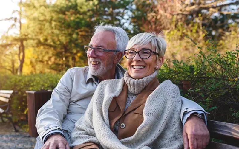 Smiling older couple sitting on bench outdoors