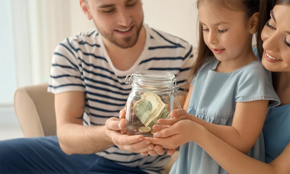 parents with young daughter holding a jar full of money