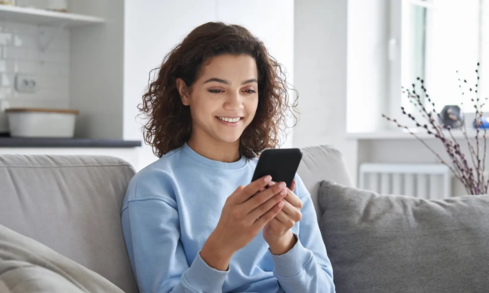 Woman sitting on couch using a phone
