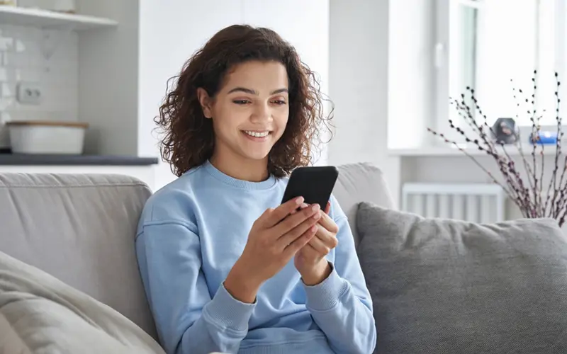 Woman sitting on couch using a phone