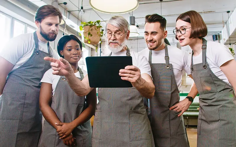 boss showing his pleased employees something on a tablet