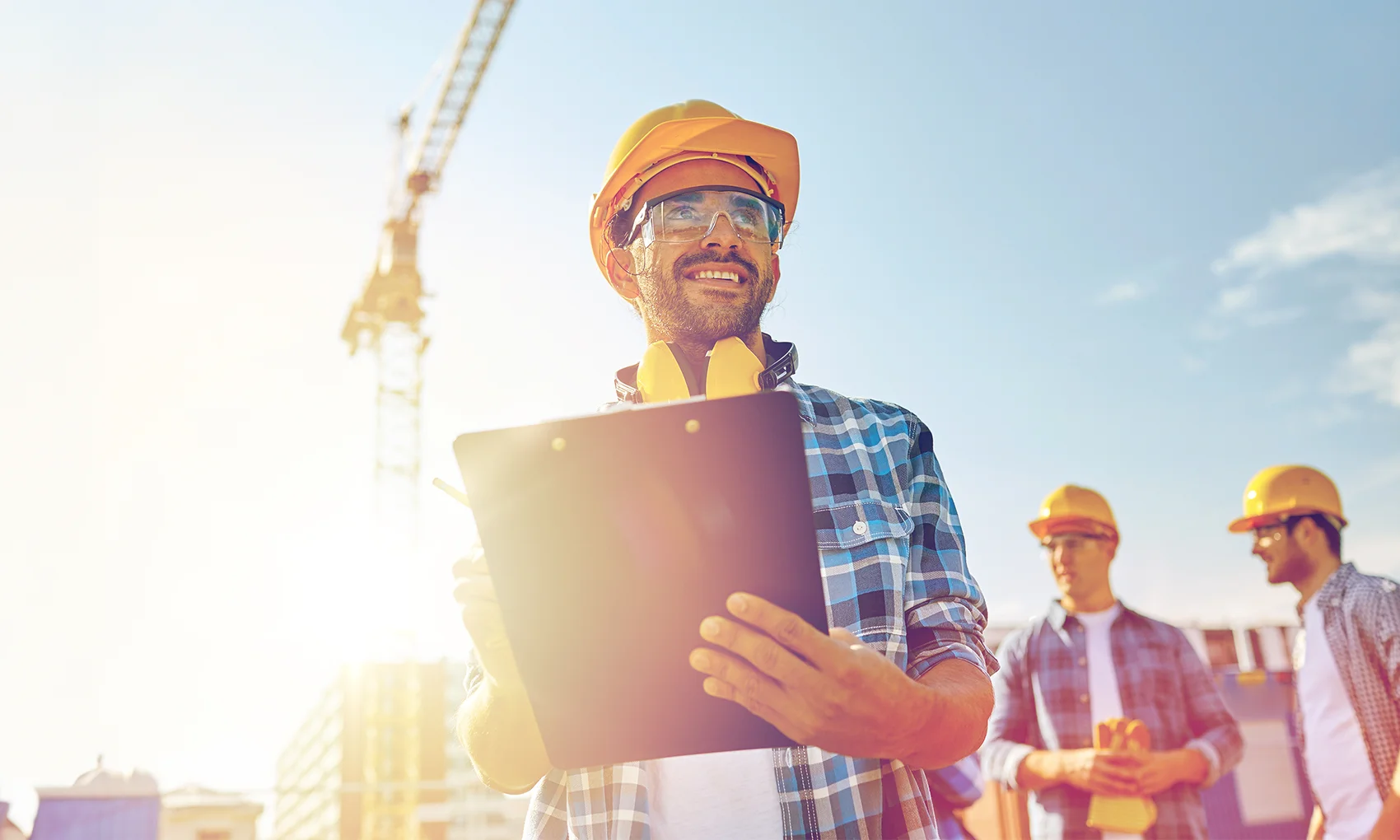 Builder in hardhat with clipboard at construction site
